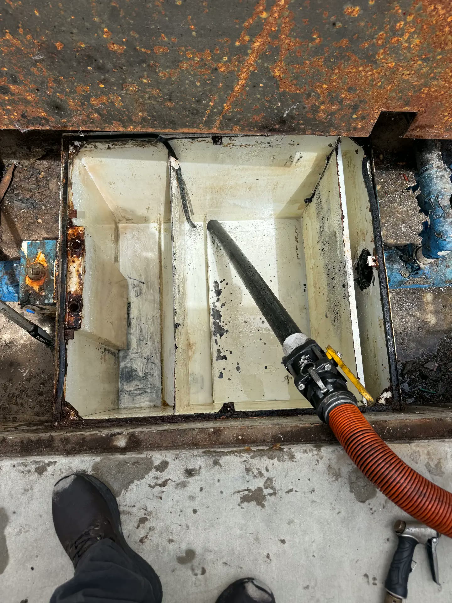Vacuum hose pumping a commercial grease trap in Riverside, California