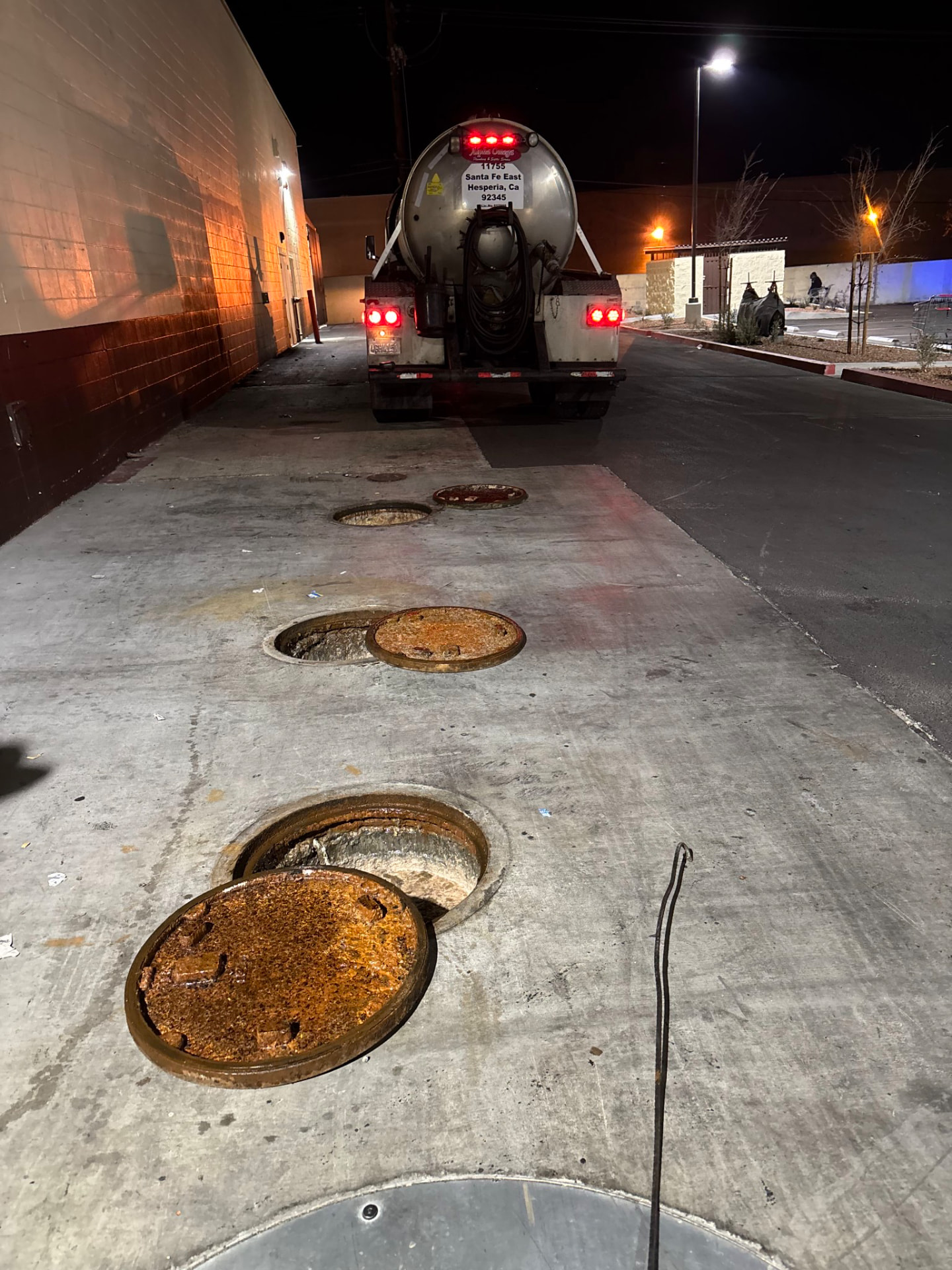 Multiple grease interceptor access lids opened for pumping behind a shopping center in Banning, California