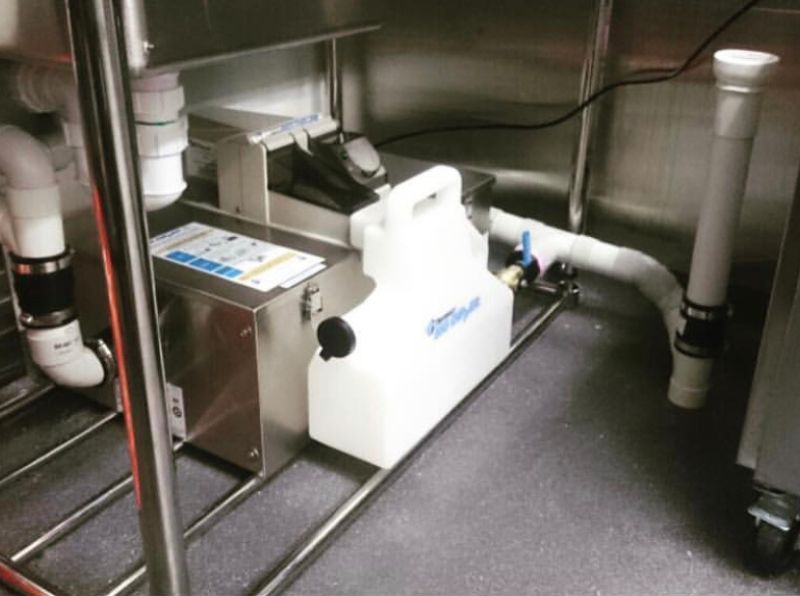 Stainless under-sink grease trap unit plumbed into a commercial kitchen