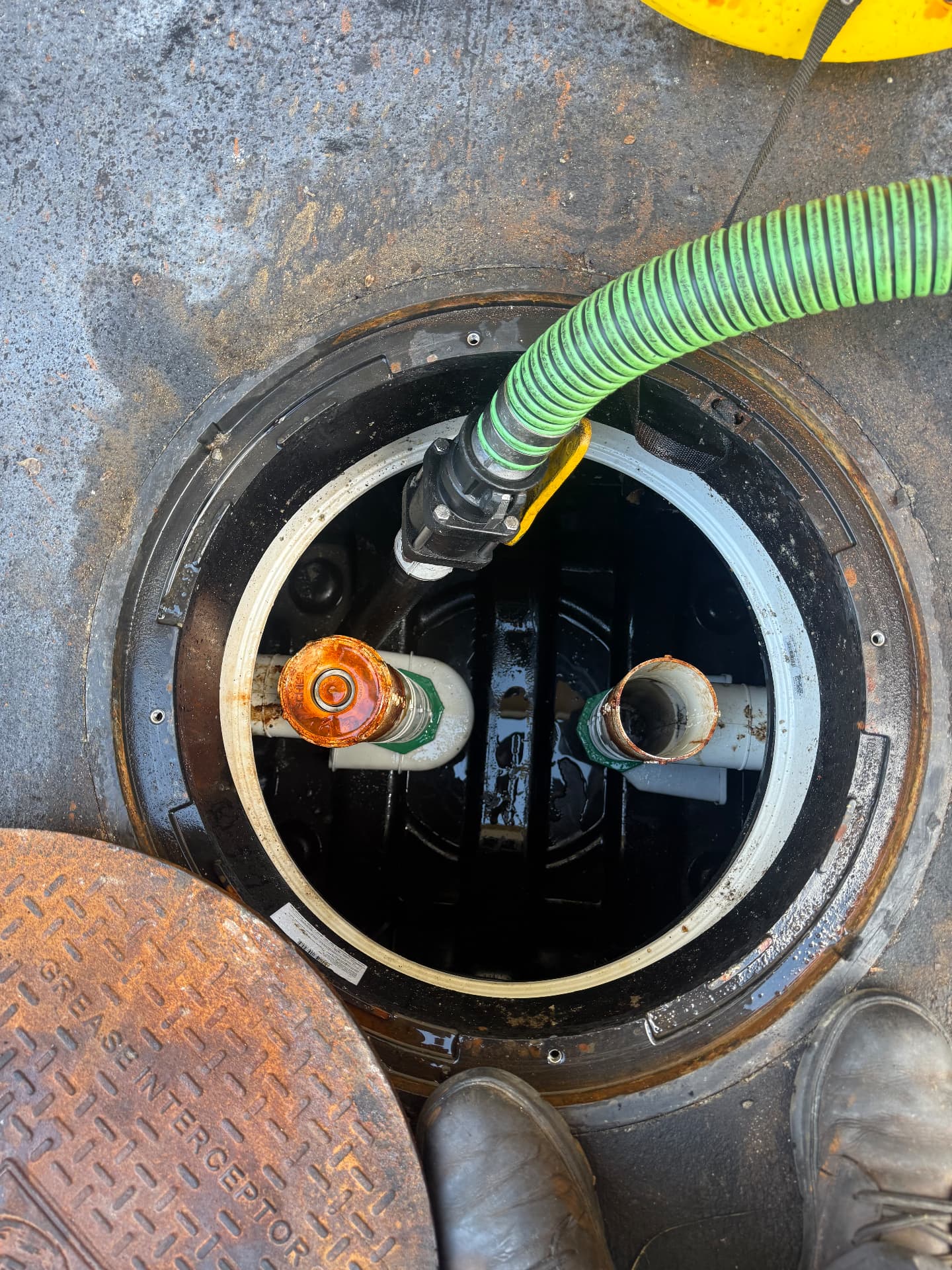 Vacuum hose inside a grease interceptor with inlet and outlet tees visible