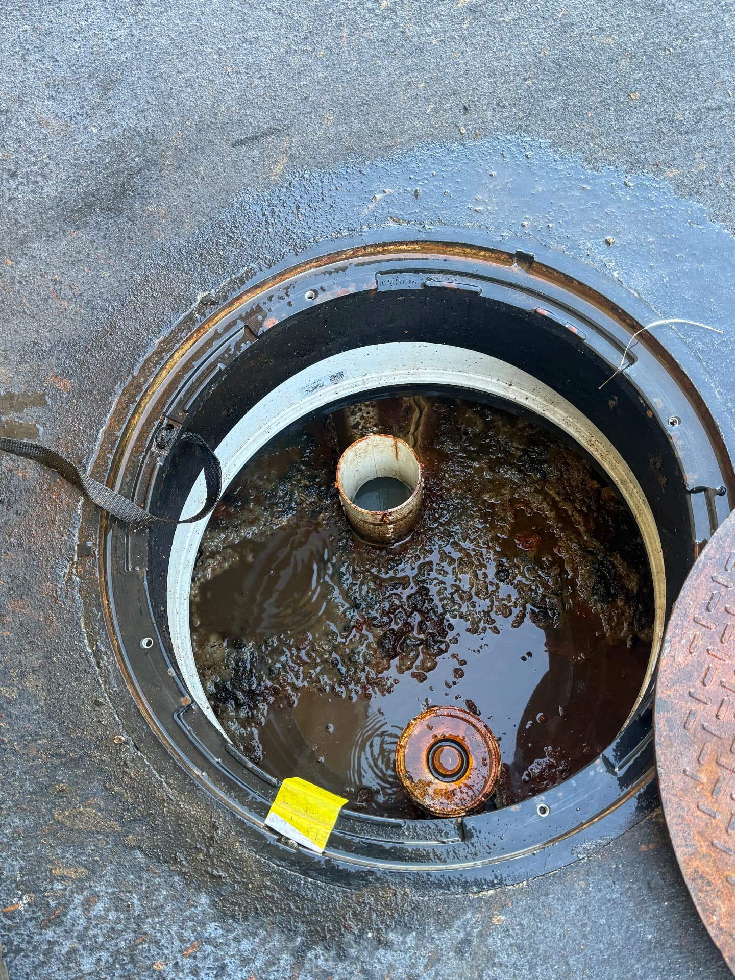 Open grease trap lid showing grease layer before cleaning