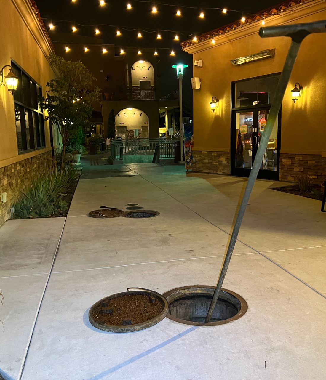 Grease interceptor opened for cleaning outside a restaurant courtyard